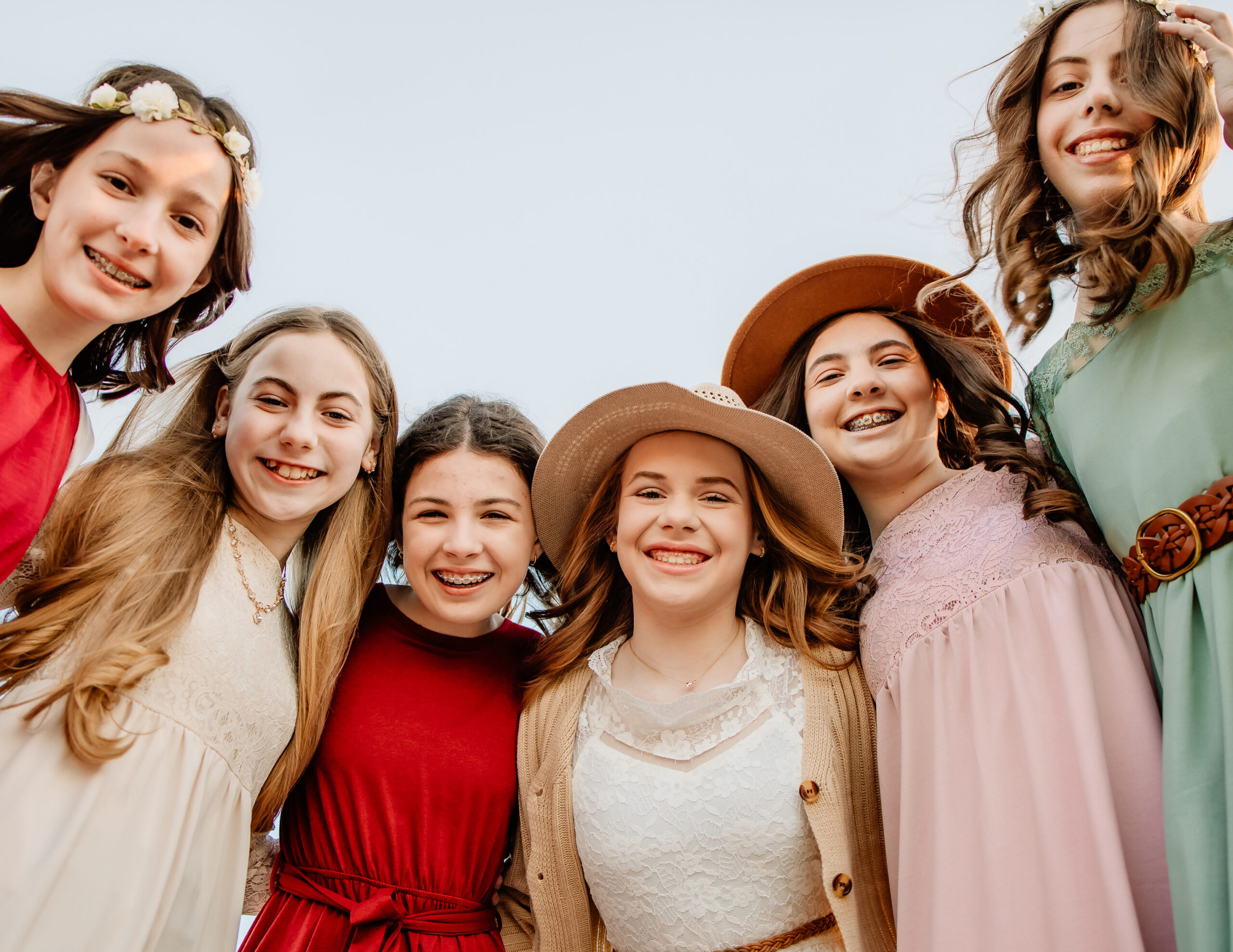 6 girls huddled together with arms around each other in the park on a sunny day in St. Louis.