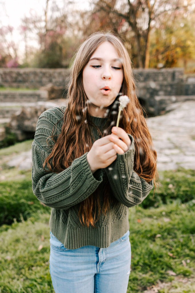 A beautiful young lady blowing a dandelion at Silvan Springs Park in St. Louis, MO.