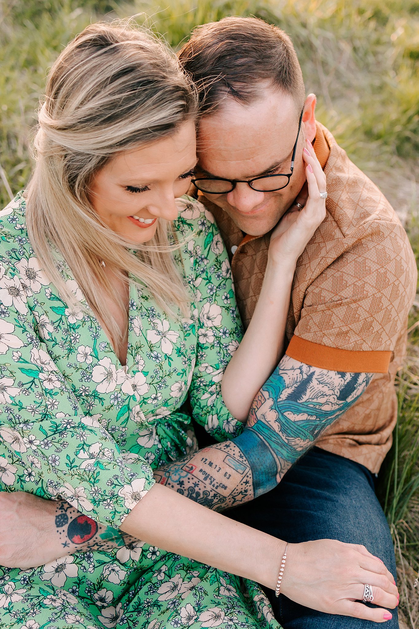 A married couple sit in a field hugging and cuddling