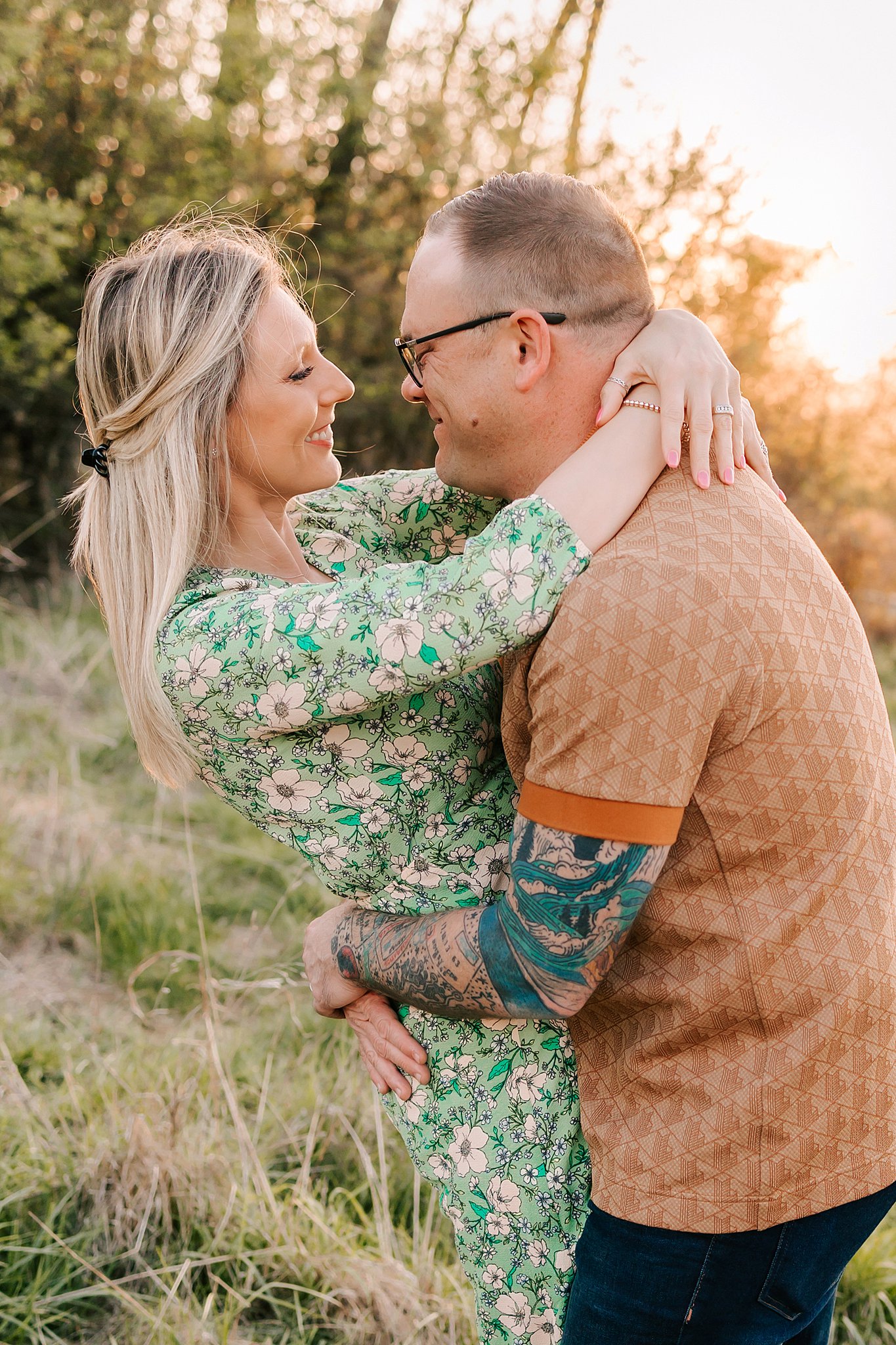 A married couple dance and hug in a field of tall grass at sunset spas in oakville