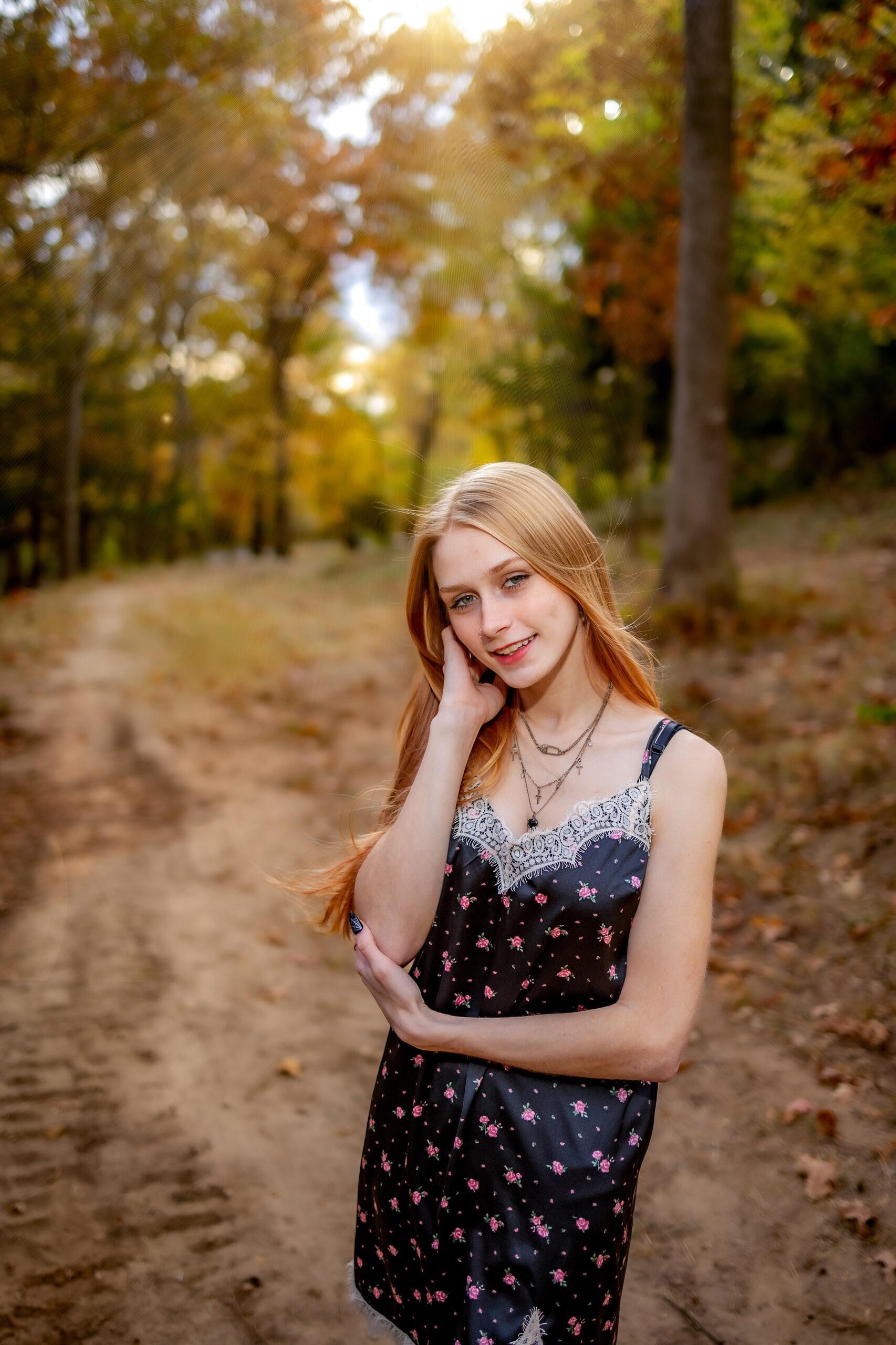 A high school senior stands in a park path in a black dress