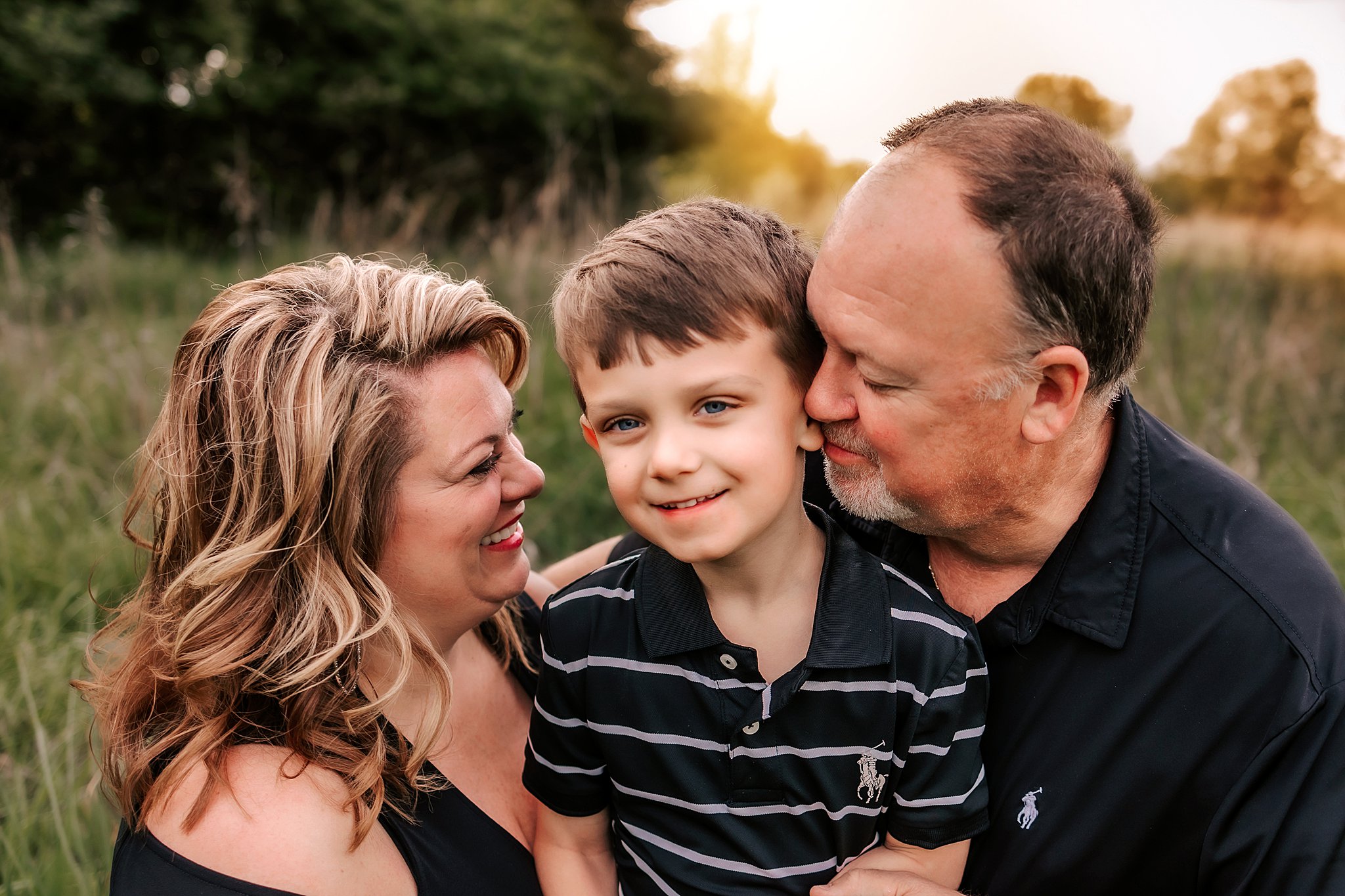 A mother and father hold their young son in their laps while wearing black