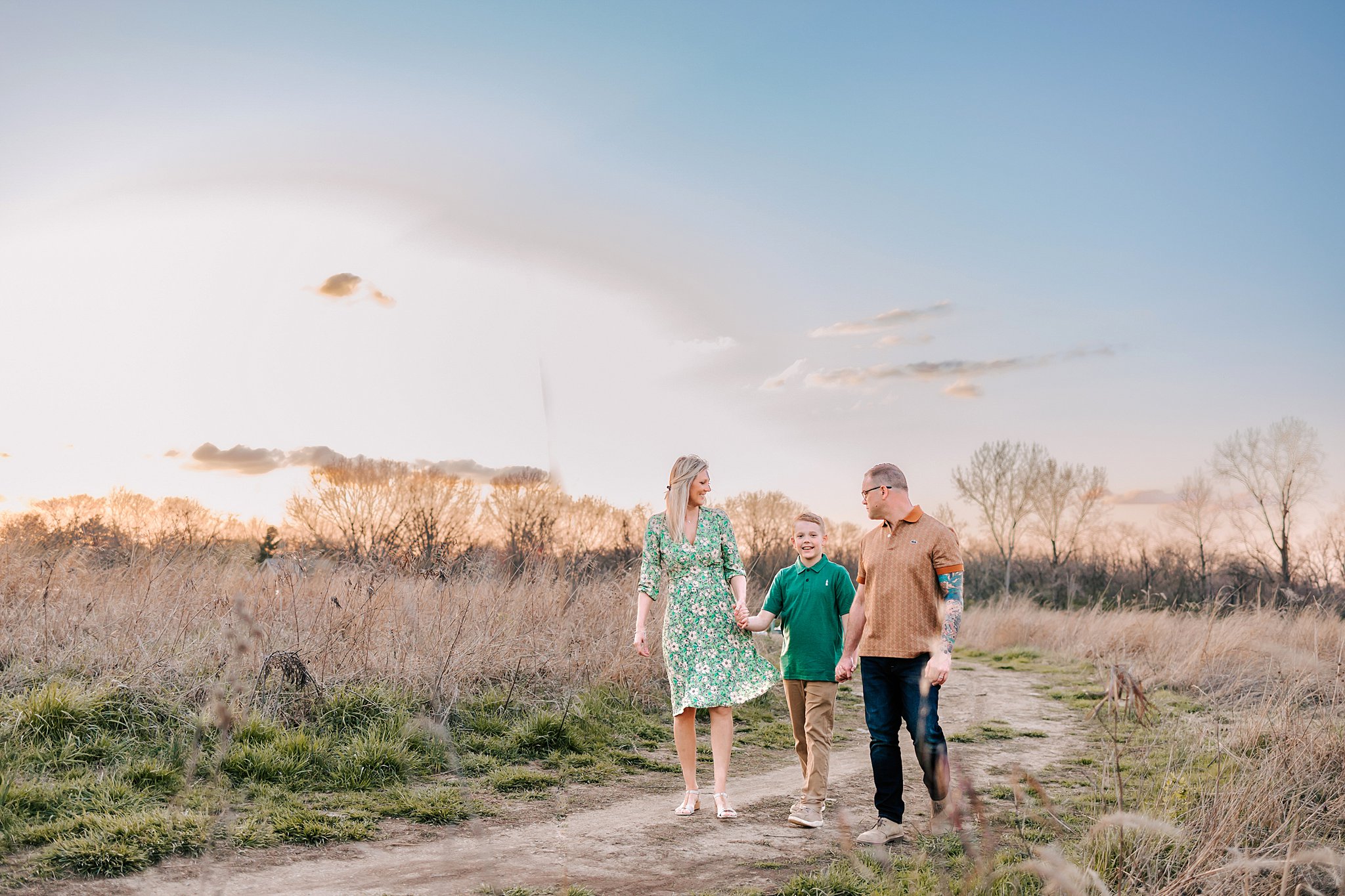 A family of three walk down a trail holding hands at sunset st louis swim lessons